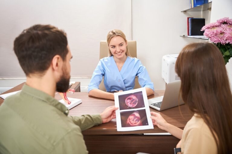 Couple looking at ultrasound scan of pregnant belly with twins near gynecologist